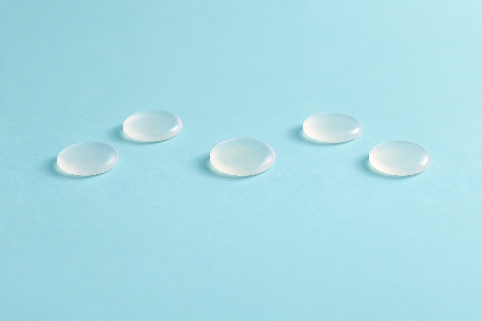 Five semi-transparent round pieces of gel spaced apart on a light blue background